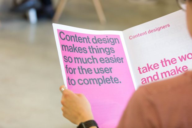 An image of someone reading a magazine about content design. On the page it says ‘Content design makes things so much easier for the user to complete’.