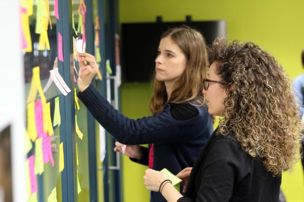 2 women looking at sticky notes on a wall