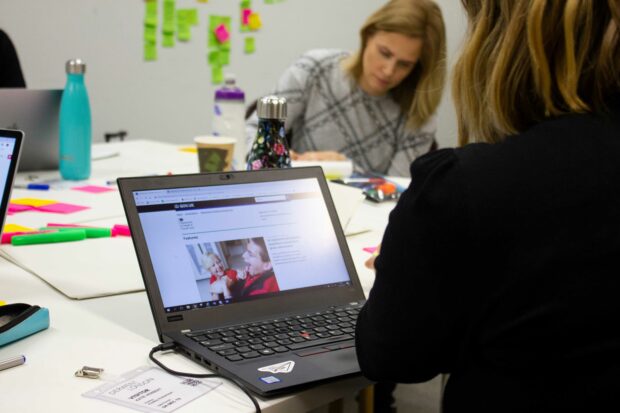 Two people in a workshop with a laptop opening showing a page on GOV.UK