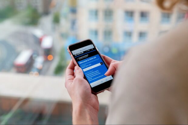 Person holding a smartphone which shows the GOV.UK homepage