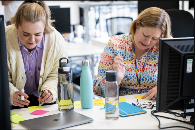 2 women working at a desk writing on post-its
